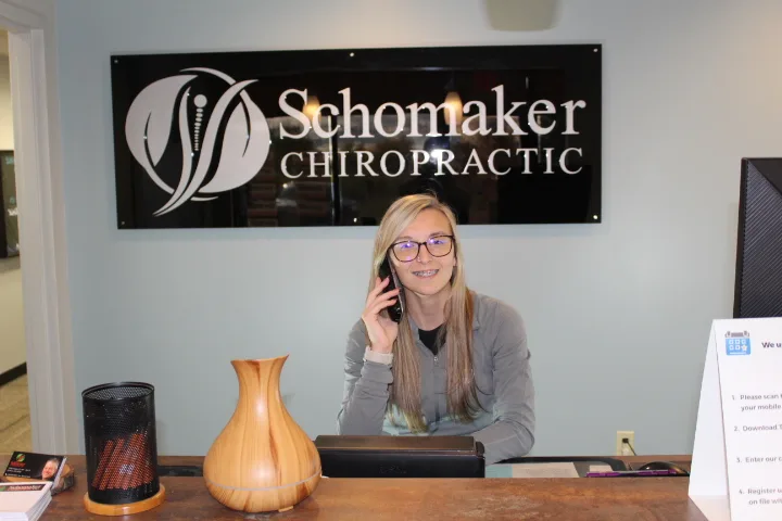Our chiropractic assistant greeting patients at the front desk of Schomaker Chiropractic Clinic in Elk River